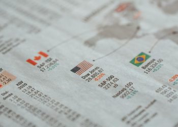 Detailed close-up of a newspaper displaying global financial market statistics and country flags.