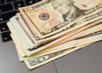 Stack of US dollar bills on a keyboard, symbolizing digital finance and wealth.