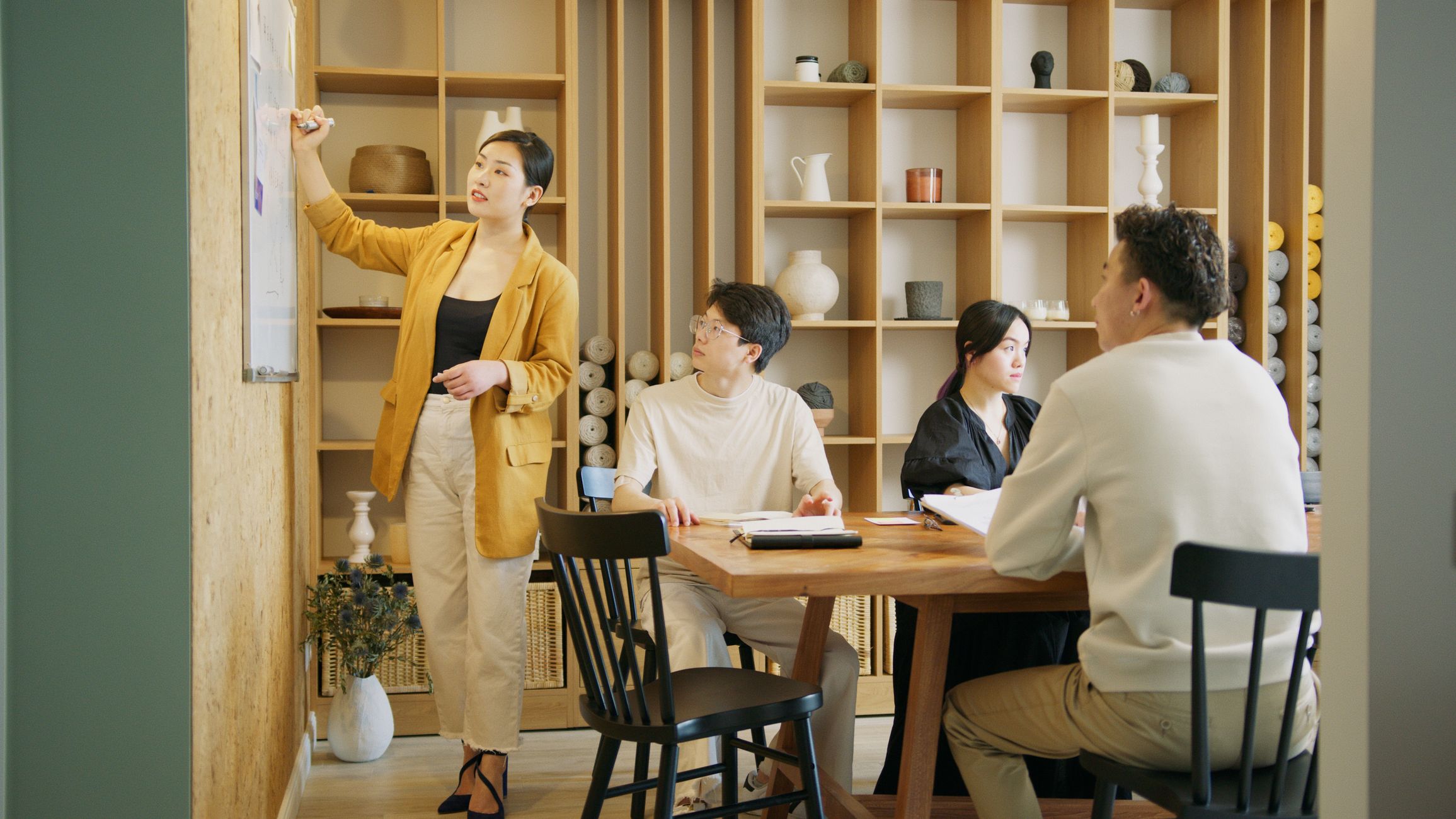 A group of professionals brainstorming and planning on a whiteboard in a stylish office setting.