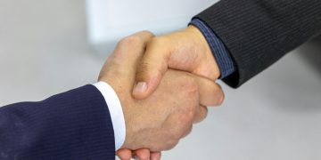 Close-up of two businessmen shaking hands, symbolizing agreement and partnership.