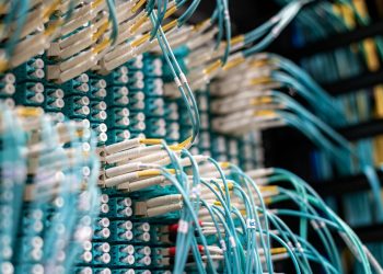 From below of long thin blue cables connected to row of small white connectors on system block in data center