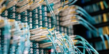 From below of long thin blue cables connected to row of small white connectors on system block in data center