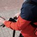 A delivery person riding an electric scooter using a smartphone for navigation outdoors.
