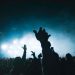 Exciting concert scene with people raising hands, set against stunning lights.