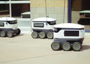 Autonomous delivery robots on a city sidewalk demonstrating modern technology for urban mobility.