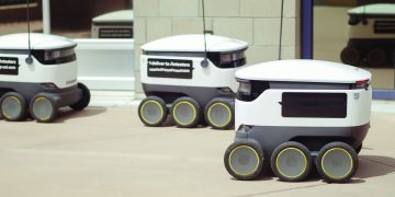 Autonomous delivery robots on a city sidewalk demonstrating modern technology for urban mobility.
