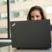 Focused woman using a laptop in a brightly lit office setting, showcasing modern work technology.