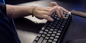 Close-up of a hand typing on a mechanical keyboard, highlighting modern technology and work.