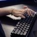 Close-up of a hand typing on a mechanical keyboard, highlighting modern technology and work.