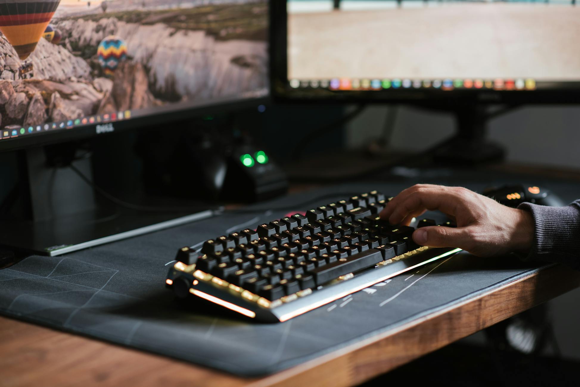 Crop anonymous male using contemporary computer with big monitors and typing on backlit keyboard