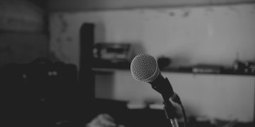 Artistic black and white shot of a music studio with a focus on a microphone. Perfect for music-themed projects.