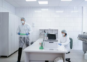 Researchers conducting experiments in a clean, modern laboratory environment wearing protective gear.