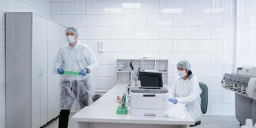 Researchers conducting experiments in a clean, modern laboratory environment wearing protective gear.