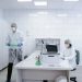 Researchers conducting experiments in a clean, modern laboratory environment wearing protective gear.
