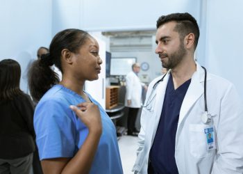 Medical professionals discussing patient care in a hospital hallway.