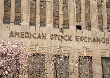 Facade of the American Stock Exchange Building in New York City during spring with blooming trees.