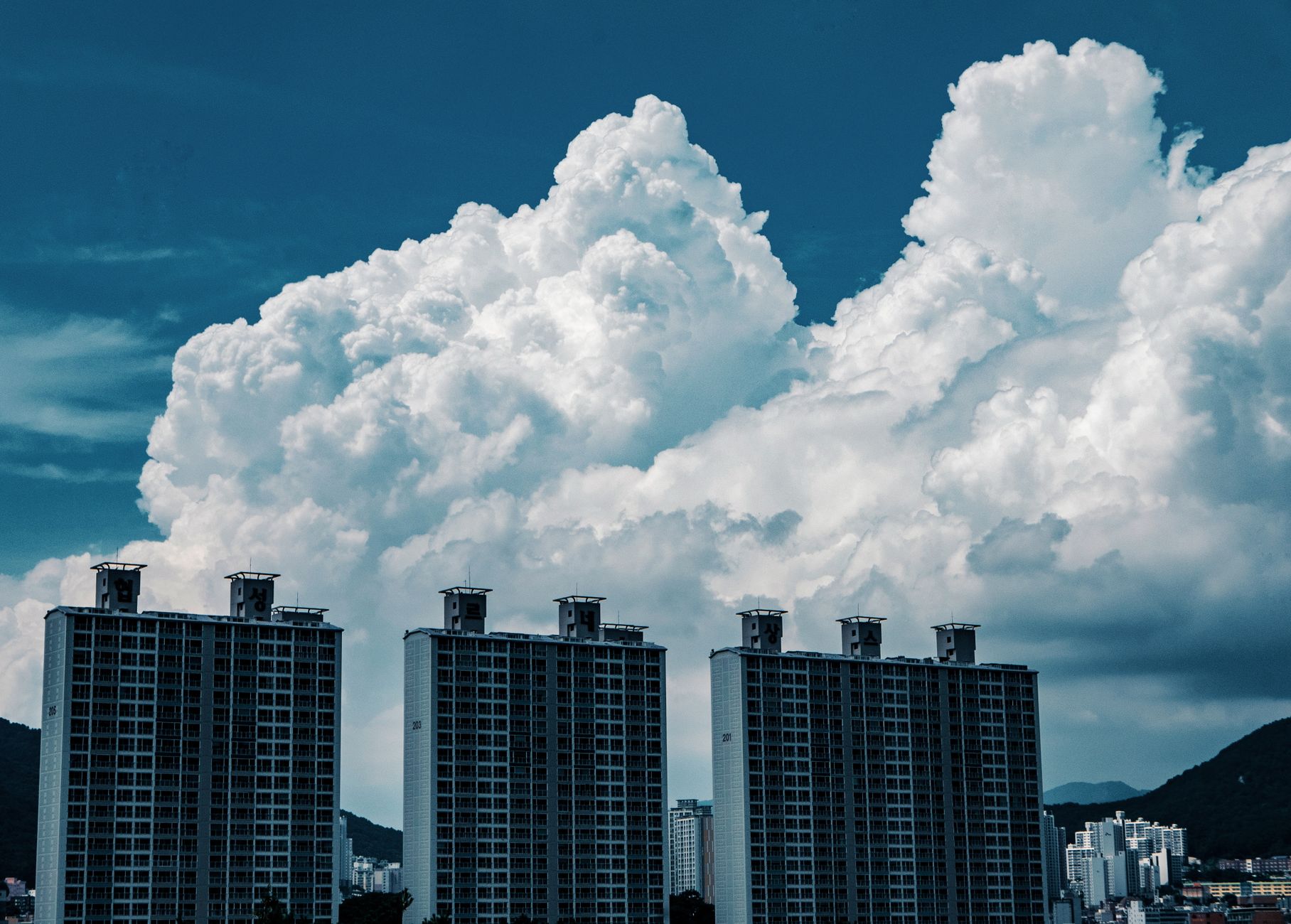 High-rise urban buildings under striking cumulus clouds in a cityscape.
