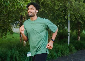 Adult male running outdoors in a lush park, embracing a healthy lifestyle.
