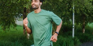 Adult male running outdoors in a lush park, embracing a healthy lifestyle.