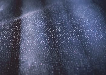 Close-up of shimmering bokeh lights on a textured dark surface creating an abstract pattern.