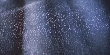 Close-up of shimmering bokeh lights on a textured dark surface creating an abstract pattern.