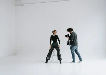 Photographer and model in a modern studio capturing stunning portraits on a white background.