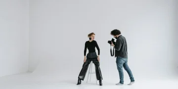 Photographer and model in a modern studio capturing stunning portraits on a white background.