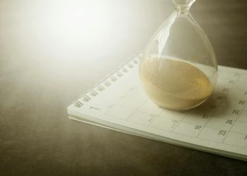 An hourglass on a calendar captures the essence of time management and urgency.