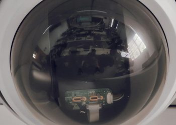 A close view of a surveillance dome camera reflecting an indoor setting.