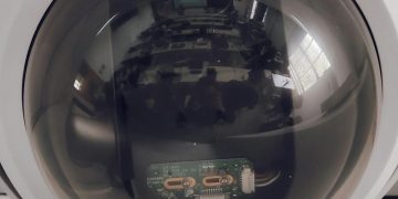 A close view of a surveillance dome camera reflecting an indoor setting.