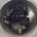A close view of a surveillance dome camera reflecting an indoor setting.