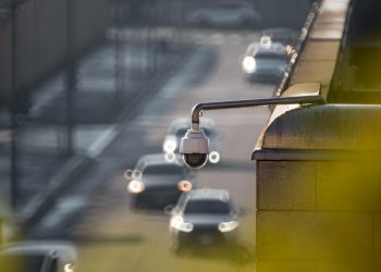 CCTV camera monitoring city traffic on a busy road with blurred vehicles in the background.
