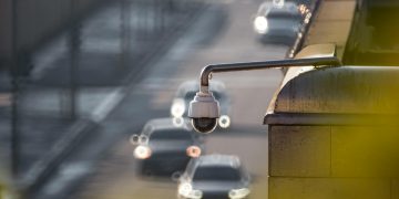 CCTV camera monitoring city traffic on a busy road with blurred vehicles in the background.