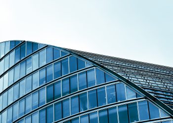 Sleek modern architecture with curved glass facade in an urban setting.