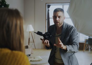 Photographer instructing model during an indoor studio session with professional lighting.