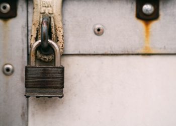 Close-up of a rusty metal padlock on a weathered door, highlighting security and decay.