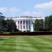 Iconic view of the White House with lush gardens and a central fountain on a sunny day.