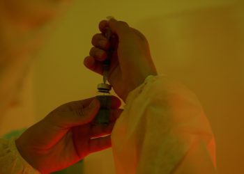Close-up of a scientist handling a syringe and vial, highlighting laboratory work.