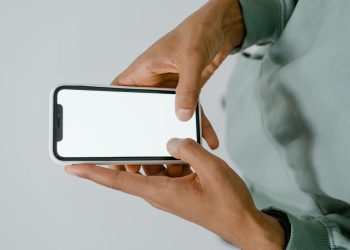 Hands holding a smartphone with a blank screen, perfect for mockups or copy space.