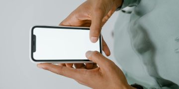 Hands holding a smartphone with a blank screen, perfect for mockups or copy space.