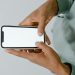 Hands holding a smartphone with a blank screen, perfect for mockups or copy space.