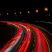 A captivating long exposure of a highway at night, showcasing vibrant light trails under streetlamps.