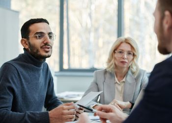 Three diverse colleagues engaging in a business discussion in a modern office setting.