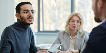 Three diverse colleagues engaging in a business discussion in a modern office setting.