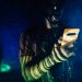 A person with futuristic makeup using a smartphone in a cyberpunk setting.