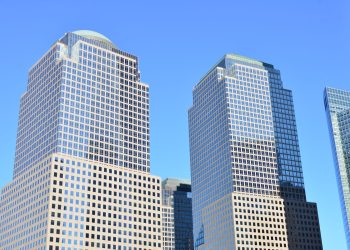 Stunning low-angle view of modern skyscrapers in downtown New York under a clear blue sky.