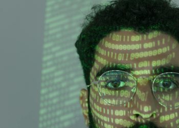 Close-up of a man with binary code projected on his face, symbolizing cybersecurity.