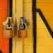 Close-up of two brass padlocks securing a vibrant graffiti-painted door, symbolizing security.