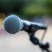Soft focus of contemporary microphone on holder placed on stage during performance in park