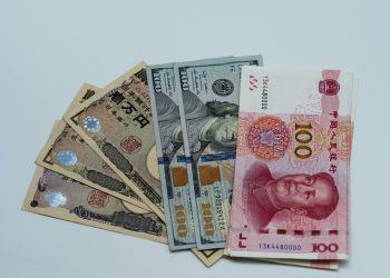 Various international currency notes including US dollars, yen, and yuan arranged on a surface.